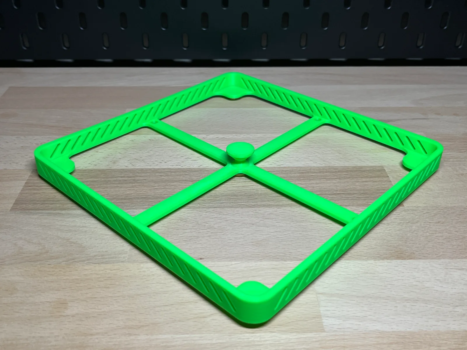 The green frame from above at an angle on the workbench, the cross in the middle and the vented sides visible