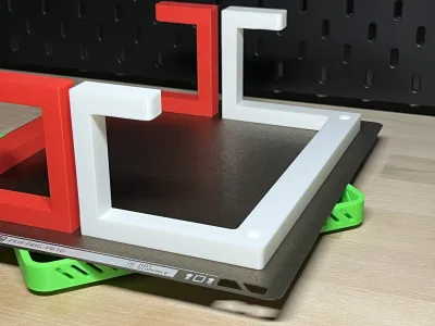 A black print plate lies in a white frame, a red one behind it — the plate rests clear of the surface