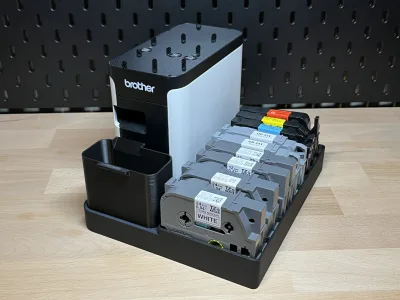The loaded station from above at an angle: the printer on the left, nine tape cassettes next to it, the catch tray at the front