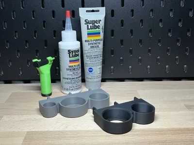 Der graue Halter auf der Werkbank, dahinter die Flaschen Super Lube und Synco Lube