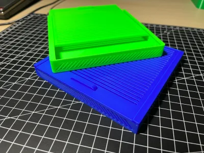 Grüne und blaue Box übereinander auf der Schneidematte, beide mit geripptem Deckel und schräger Seitenwand