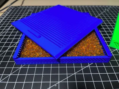 Die blaue Box mit abgehobenem Deckel, das Fach ist mit orangefarbenen Silikagel-Kugeln gefüllt