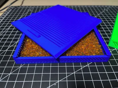 Two blue boxes with ribbed lids on the cutting mat, one open and filled with orange silica gel beads