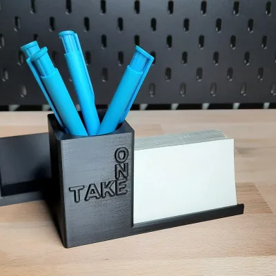 The TAKE ONE variant from the front, four blue pens in the cup, white cards in the tray